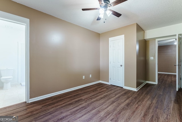 unfurnished bedroom with dark hardwood / wood-style flooring, a textured ceiling, and ceiling fan