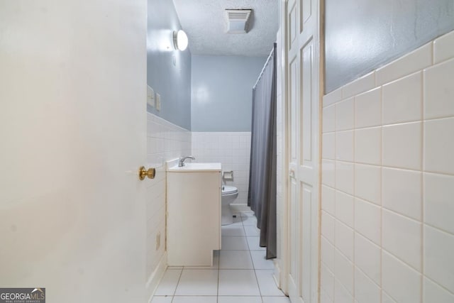 bathroom featuring vanity, tile walls, tile flooring, a textured ceiling, and toilet