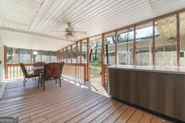 unfurnished sunroom featuring vaulted ceiling, wooden ceiling, ceiling fan, and a wealth of natural light