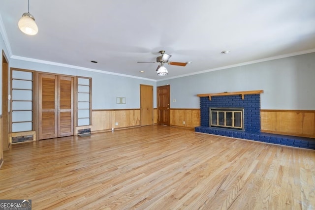 unfurnished living room featuring ornamental molding, a fireplace, ceiling fan, and light hardwood / wood-style flooring