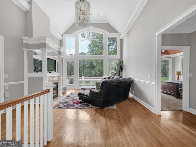 living room featuring a wealth of natural light, ornamental molding, a chandelier, and light wood-type flooring