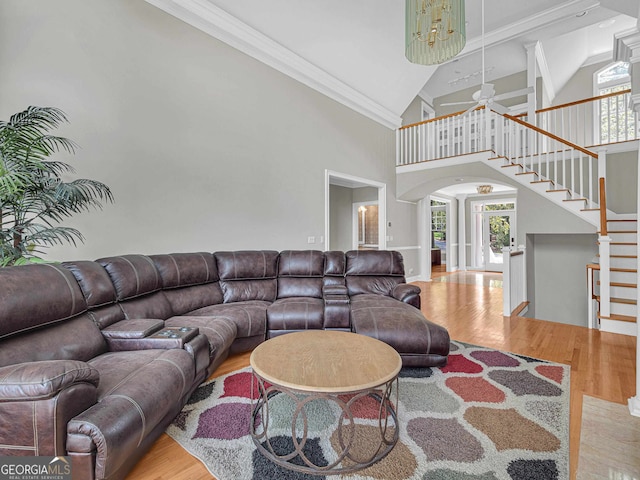 living room featuring light hardwood / wood-style flooring, ceiling fan, ornamental molding, and high vaulted ceiling