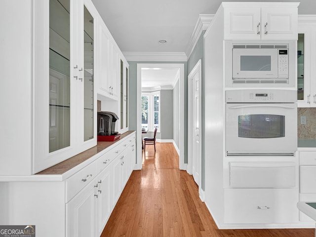 kitchen featuring white appliances, white cabinets, ornamental molding, and light hardwood / wood-style flooring