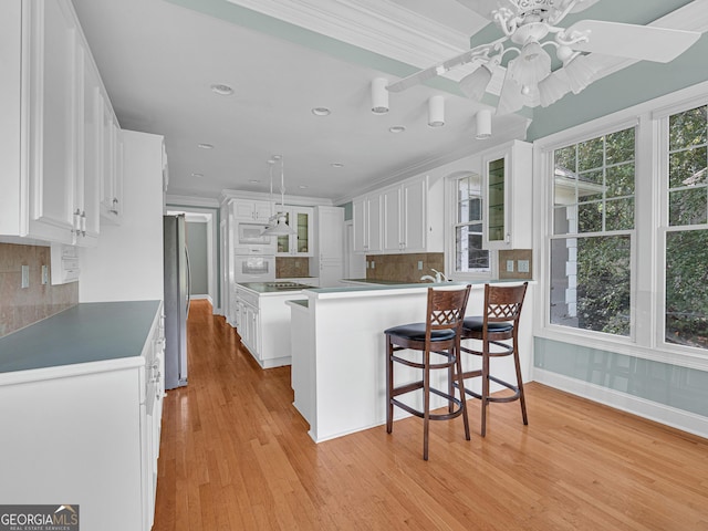 kitchen with ceiling fan, hanging light fixtures, light hardwood / wood-style flooring, backsplash, and stainless steel refrigerator