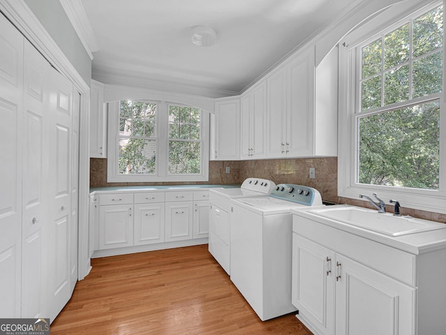 laundry area with cabinets, light hardwood / wood-style floors, sink, washer and clothes dryer, and ornamental molding