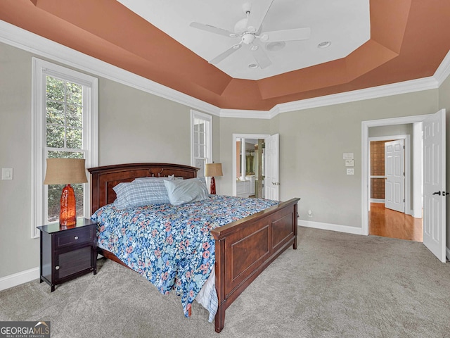 bedroom with ceiling fan, light colored carpet, ornamental molding, and a tray ceiling