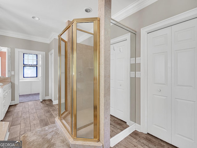 bathroom with walk in shower, ornamental molding, vanity, and wood-type flooring