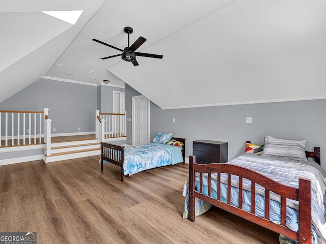 bedroom with crown molding, vaulted ceiling with skylight, wood-type flooring, and ceiling fan