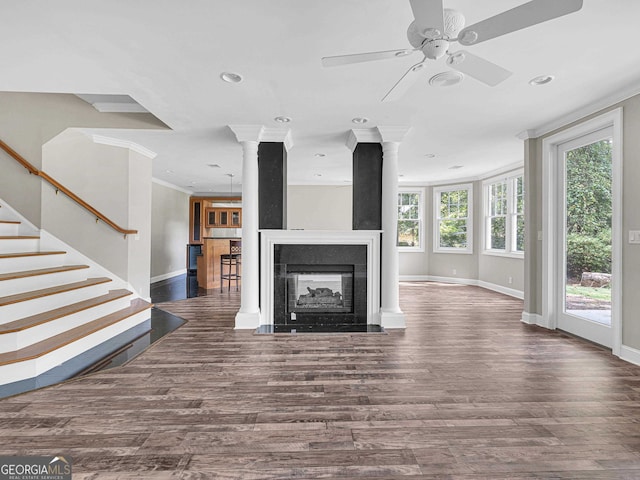 unfurnished living room with ornamental molding, ceiling fan, ornate columns, and dark hardwood / wood-style flooring