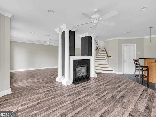 unfurnished living room featuring a tile fireplace, crown molding, ceiling fan, and dark wood-type flooring