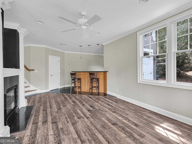 unfurnished living room featuring dark hardwood / wood-style floors, ornamental molding, and ceiling fan