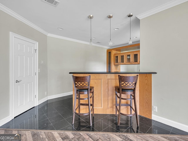 kitchen with crown molding, hanging light fixtures, dark wood-type flooring, and a kitchen bar