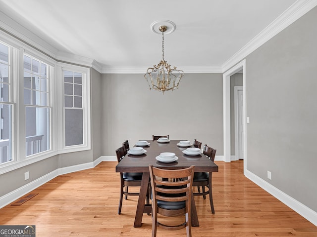 dining area featuring a notable chandelier, crown molding, and light wood-type flooring