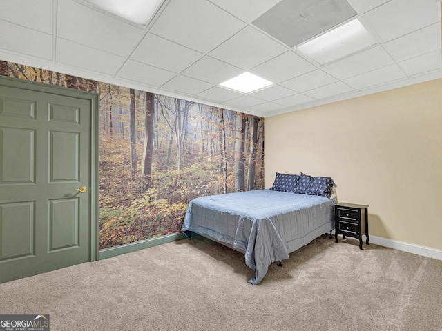 bedroom with a drop ceiling and light carpet