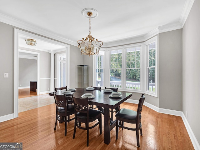 dining room with a chandelier, a healthy amount of sunlight, ornamental molding, and light hardwood / wood-style flooring