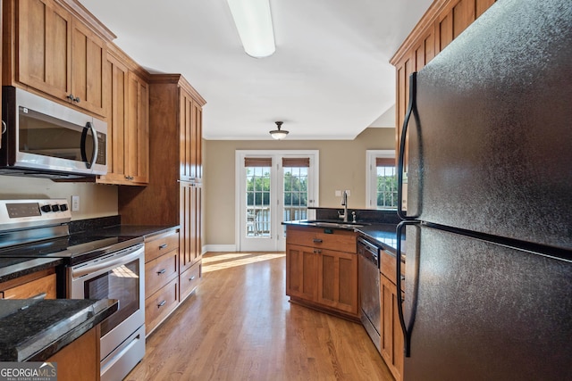 kitchen featuring light hardwood / wood-style flooring, appliances with stainless steel finishes, dark stone countertops, and sink