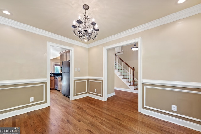 spare room with dark hardwood / wood-style floors, crown molding, and an inviting chandelier