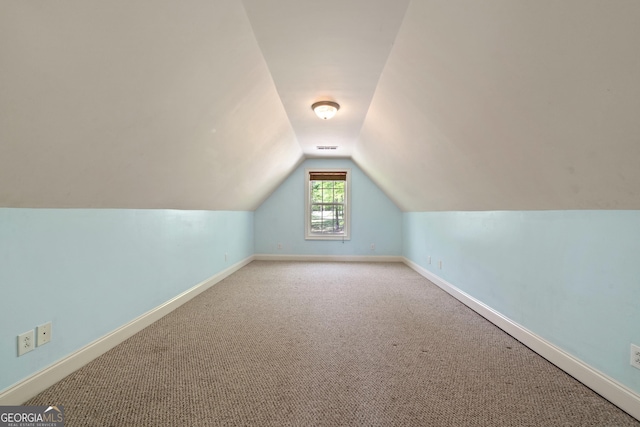 additional living space with light colored carpet and vaulted ceiling