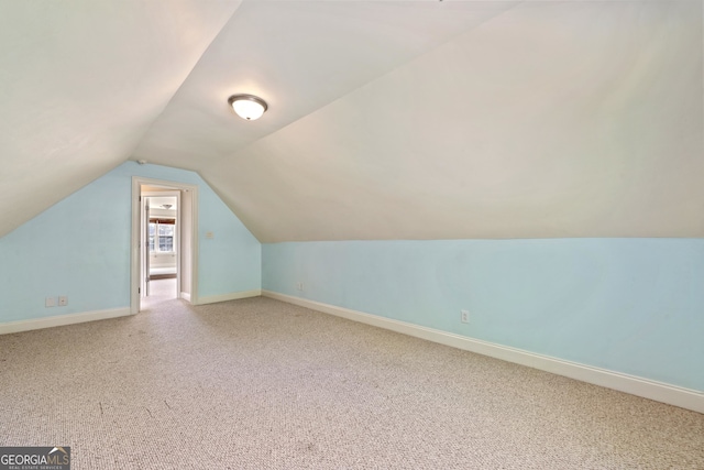 additional living space with light colored carpet and vaulted ceiling