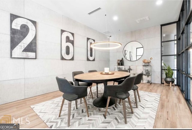 dining room featuring light hardwood / wood-style flooring and tile walls