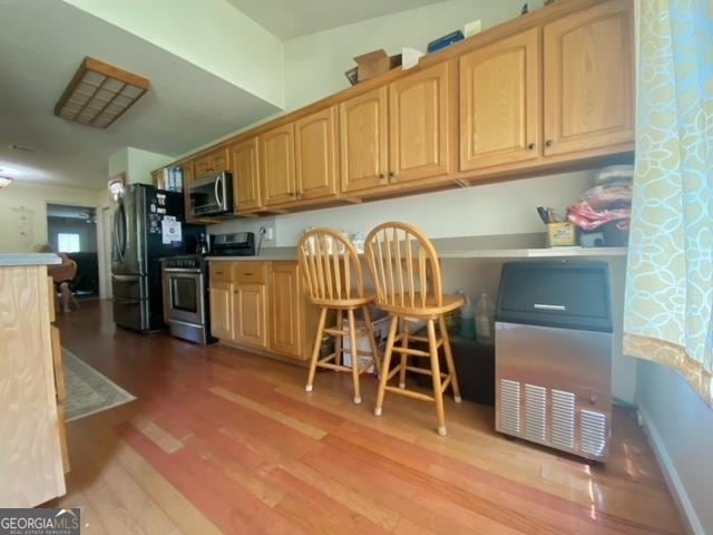 kitchen with light wood-type flooring, light brown cabinets, and appliances with stainless steel finishes