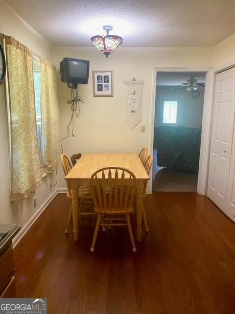 dining area featuring ceiling fan, dark wood-type flooring, and a textured ceiling