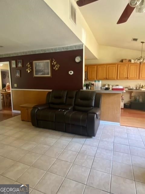 living room featuring light tile flooring, high vaulted ceiling, and ceiling fan with notable chandelier