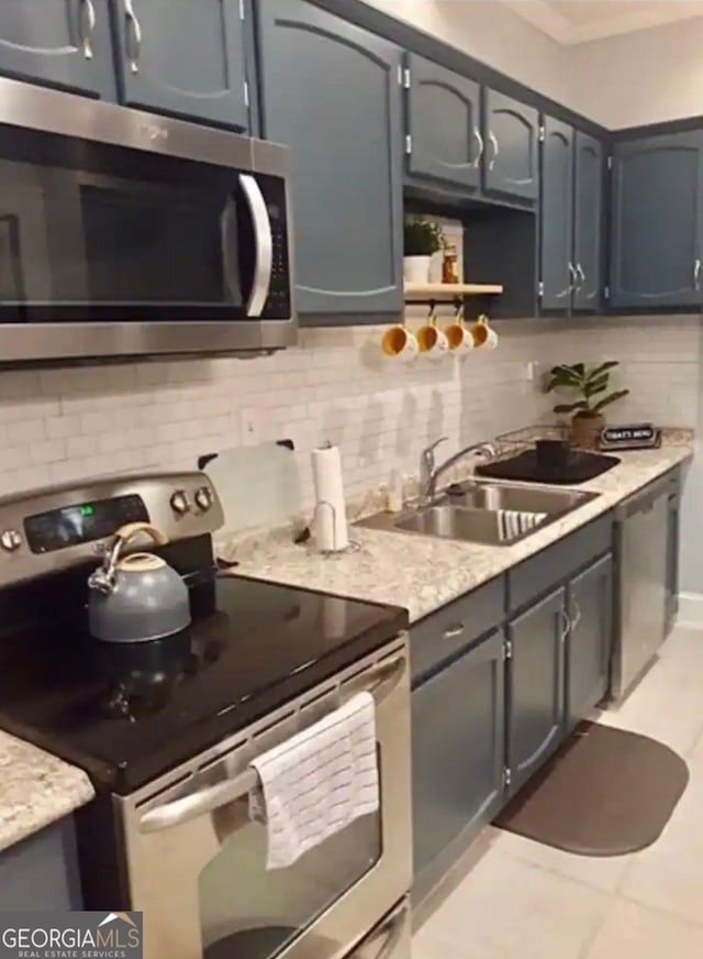 kitchen featuring appliances with stainless steel finishes, light tile flooring, tasteful backsplash, gray cabinetry, and sink