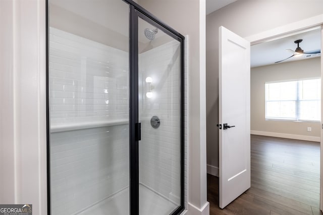 bathroom with hardwood / wood-style flooring, ceiling fan, and a shower with shower door