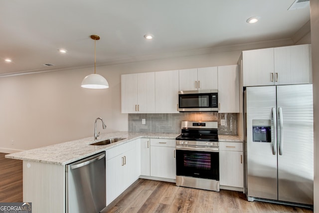 kitchen featuring hanging light fixtures, white cabinetry, sink, and appliances with stainless steel finishes