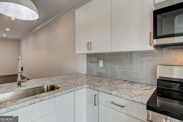 kitchen with sink, tasteful backsplash, light stone counters, crown molding, and appliances with stainless steel finishes