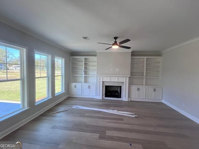 35 Fairwinds Unit 207, Waverly, GA 31565 - unfurnished living room with visible vents, ornamental molding, baseboards, ceiling fan, and a premium fireplace