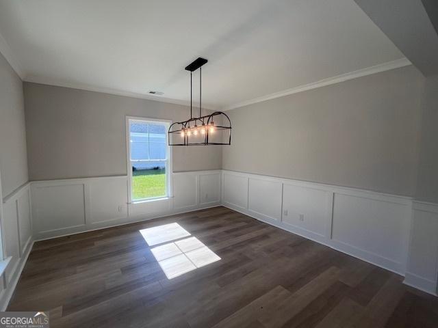 35 Fairwinds Unit 207, Waverly, GA 31565 - unfurnished dining area featuring a wainscoted wall, ornamental molding, dark wood finished floors, and a chandelier