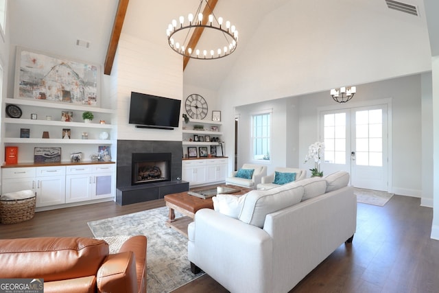 living room featuring high vaulted ceiling, dark wood-type flooring, a tile fireplace, beamed ceiling, and a chandelier