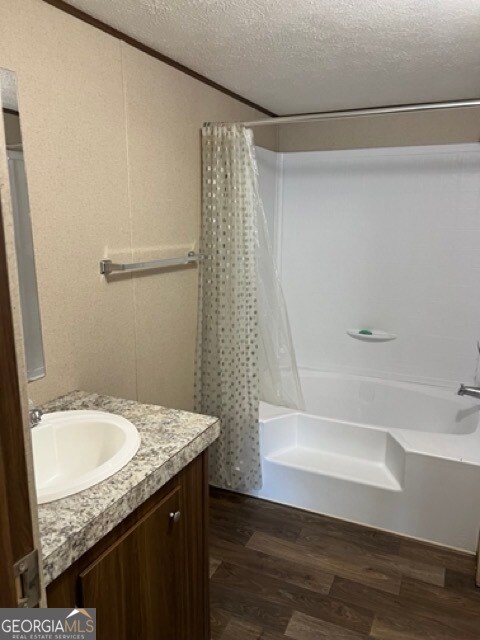 bathroom featuring a textured ceiling, shower / bath combo, hardwood / wood-style floors, and vanity