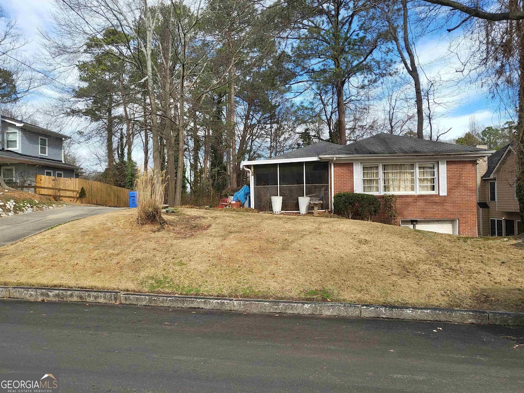 view of front of house with a sunroom and a front lawn