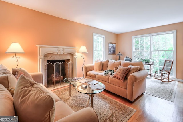 living room with a healthy amount of sunlight, a high end fireplace, and wood-type flooring