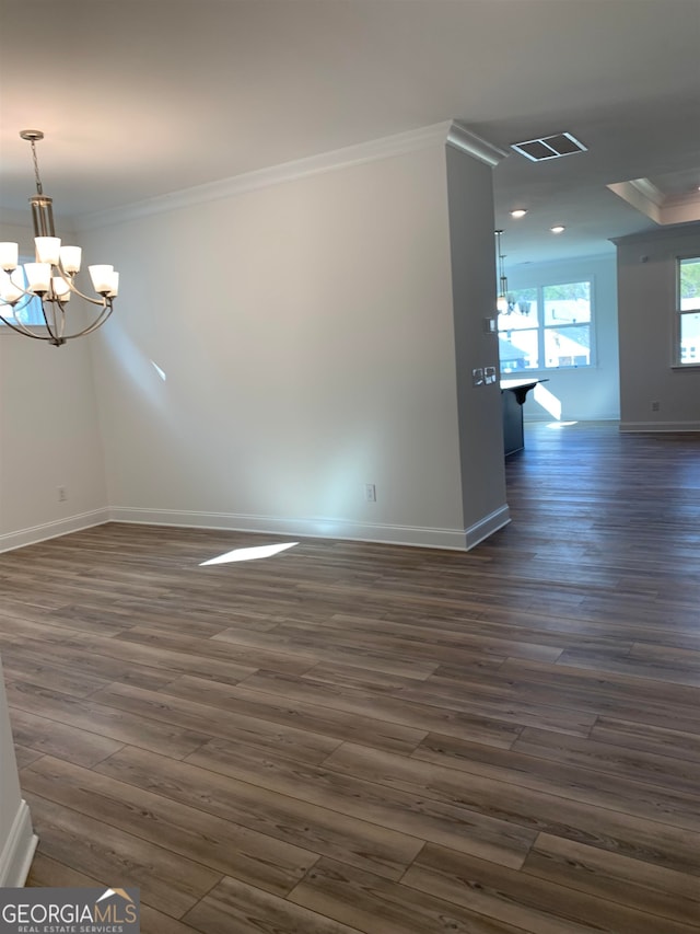 empty room featuring dark hardwood / wood-style floors, a chandelier, and ornamental molding