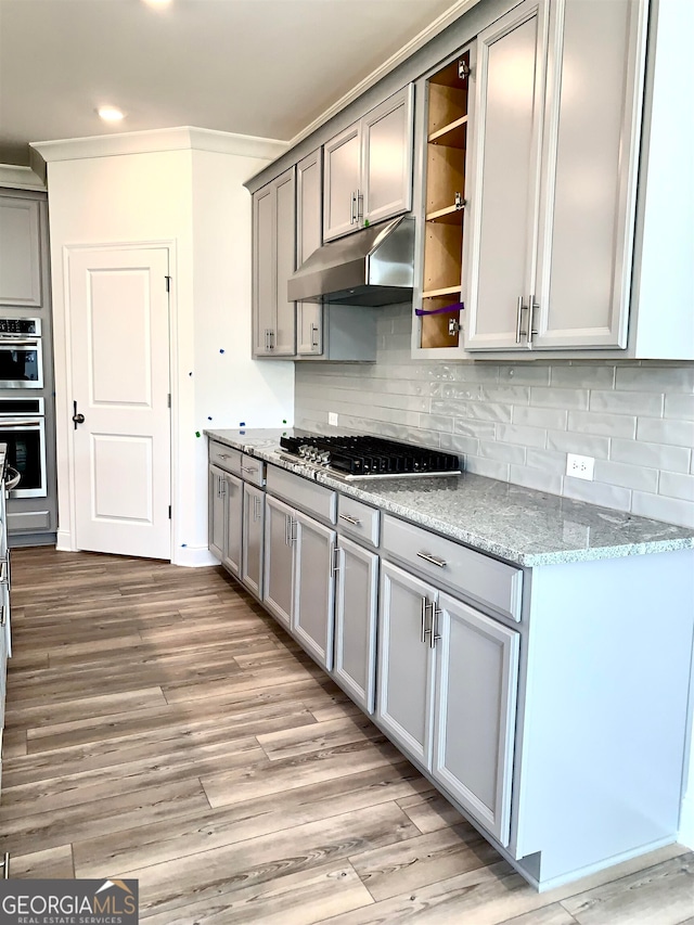 kitchen with light stone counters, light hardwood / wood-style floors, gray cabinetry, and appliances with stainless steel finishes