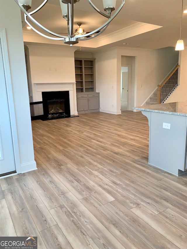 unfurnished living room with light hardwood / wood-style floors and a tray ceiling