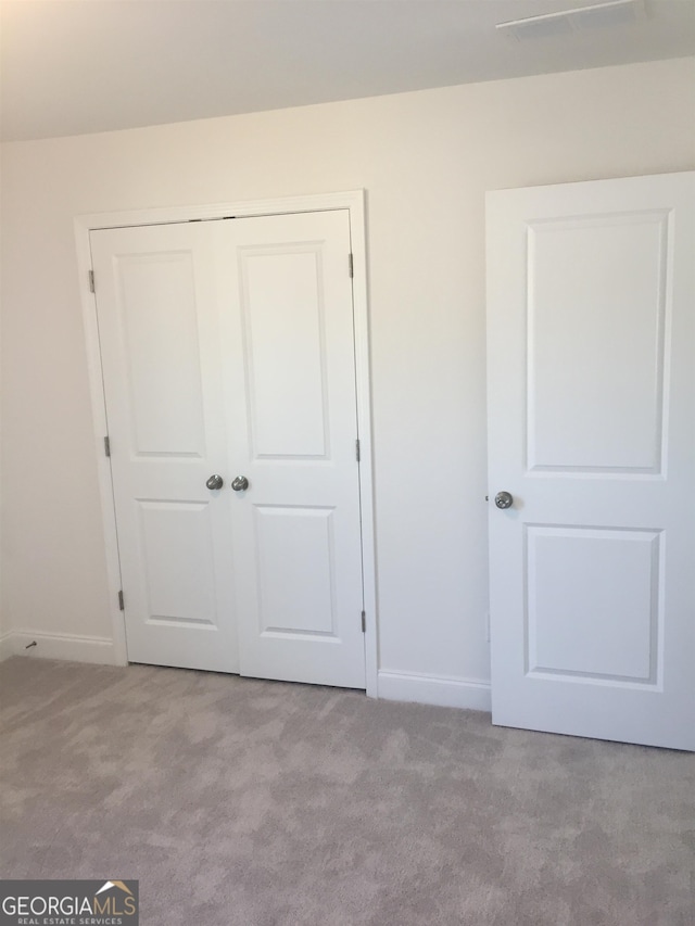 unfurnished bedroom with light colored carpet and a closet