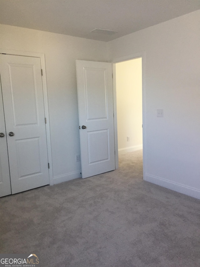 unfurnished bedroom featuring light carpet and a closet