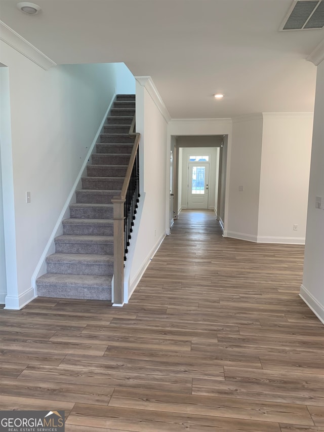 staircase with dark hardwood / wood-style flooring and ornamental molding