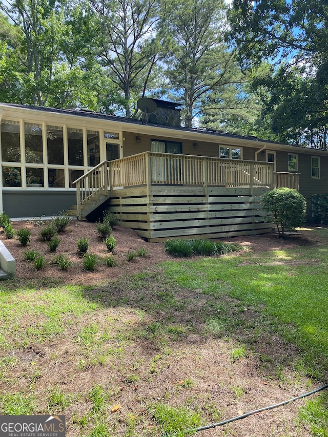 rear view of house featuring a sunroom and a wooden deck