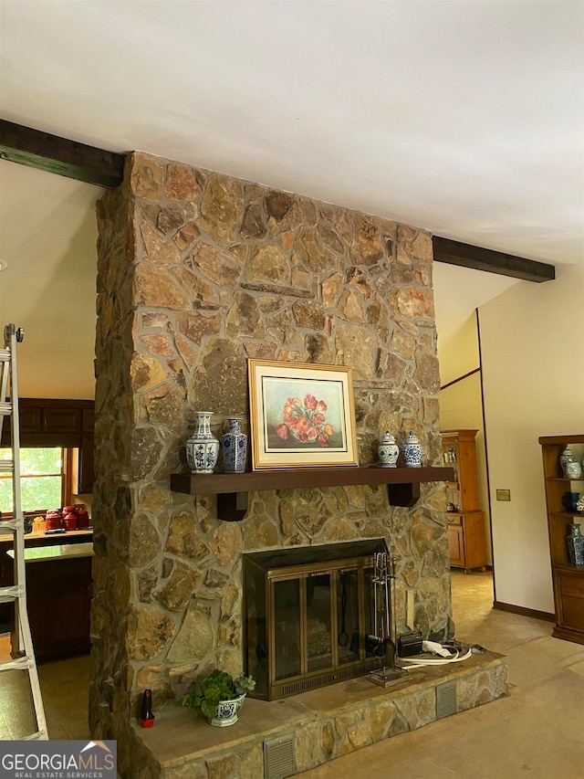 carpeted living room with a stone fireplace and beamed ceiling