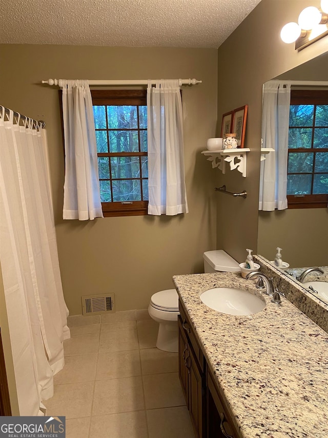 bathroom featuring vanity, a textured ceiling, tile patterned floors, and toilet