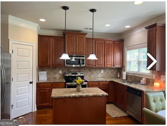 kitchen featuring sink, appliances with stainless steel finishes, hanging light fixtures, and a center island