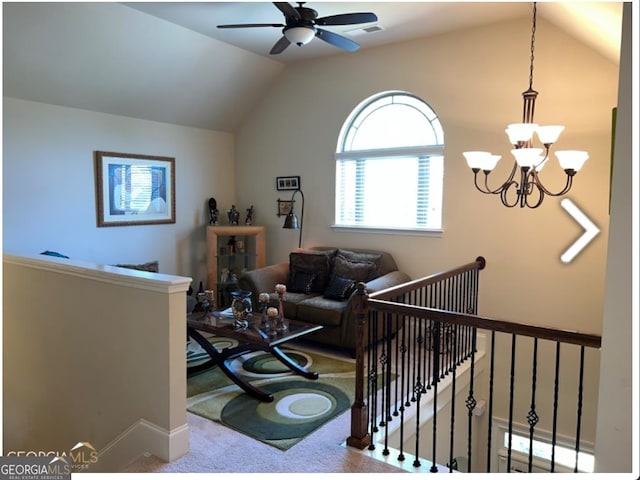 carpeted living room with ceiling fan with notable chandelier and vaulted ceiling