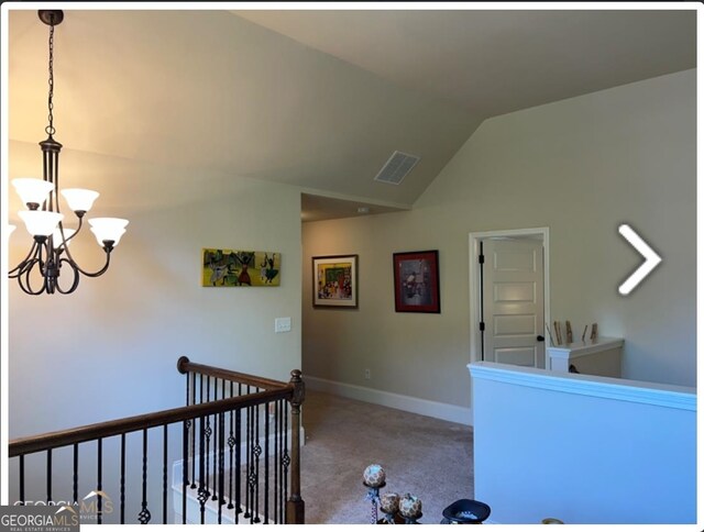 hall with carpet floors, vaulted ceiling, and a chandelier