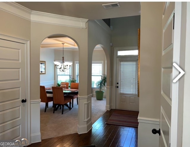 carpeted entrance foyer with a notable chandelier and crown molding